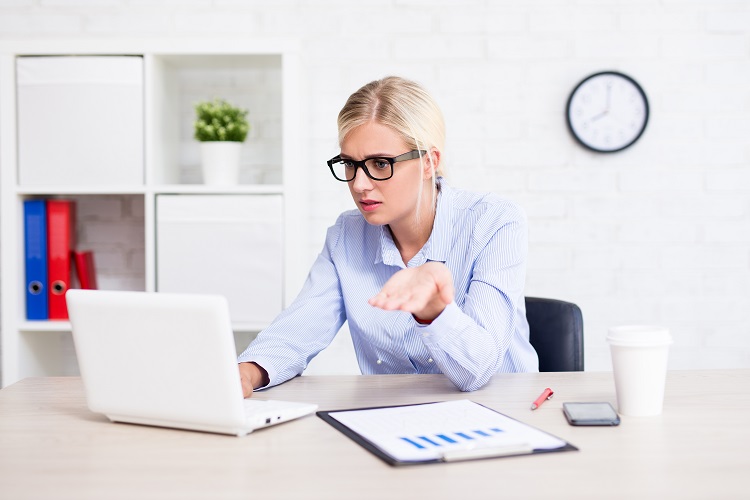 lady sitting at desk looking confused at laptop