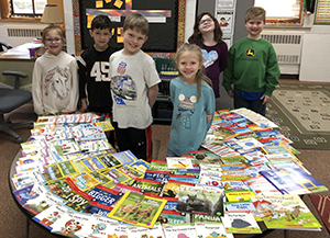students with a table full of new books in the library