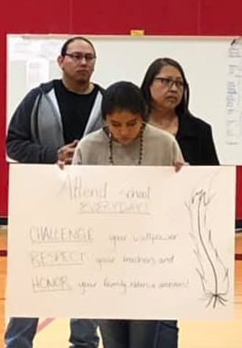 student with a sign encouraging student attendance