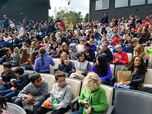 Students sit with their lunches in the theatre