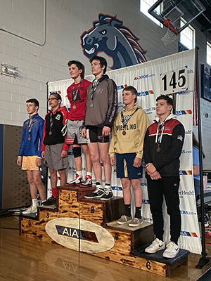 Wrestling team members stand on award stage
