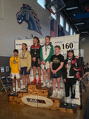 Wrestling team members stand on award stage with medals