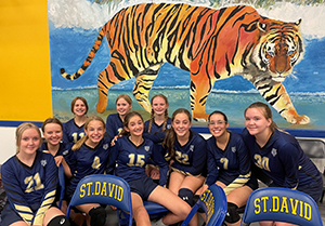 Volleyball team posing for a picture in front of a tiger mural