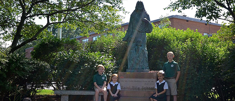Four students pose with a statue
