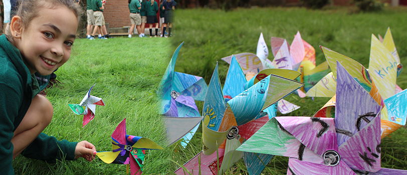 Paper windmills made from student artwork and displayed outside in the grass