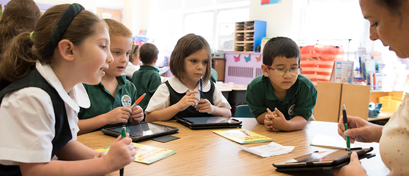 Students look at a teacher holding a tablet