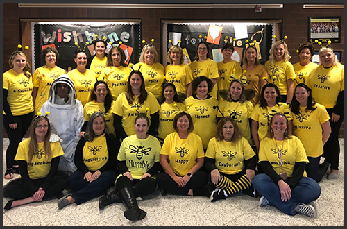 Staff members wearing bee headbands and bee t-shirts pose together
