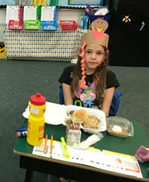 Female Student wearing turkey hat eating thanksgiving meal