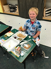 Male student eating thanksgiving meal at desk