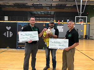 Staff members holding checks and man holding pig