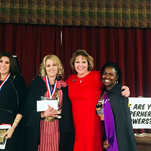 Teacher of the Year, Kelly Zamudio pictured with two other women on stage