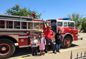 fireman and students standing in front of fire truck