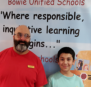 Luciano Moreno poses with staff member Travis Beck in front of a Bowie Unified Schools sign