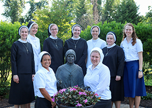 Group of nuns with a statue and flowers