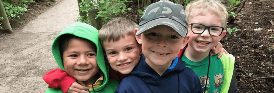 Four male students smiling on a nature trail