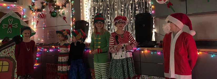 Students dressed in Christmas attire pose at a holiday event