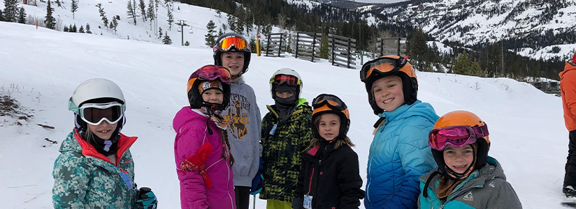 Students dressed in ski attire pose on ski slopes