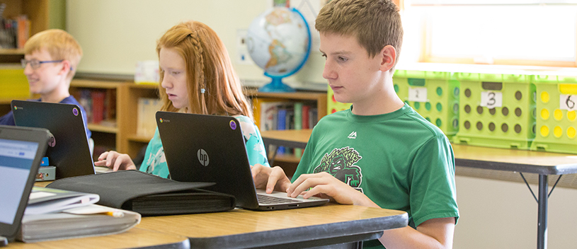 Three students use laptops in class