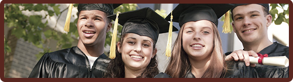 Four graduates pose together wearing graduation attire and holding a diploma