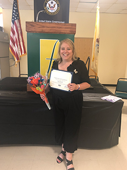 Dana Folcarelli poses with a certificate and flowers