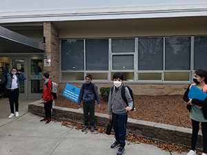 Students in masks posing for photo while entering school