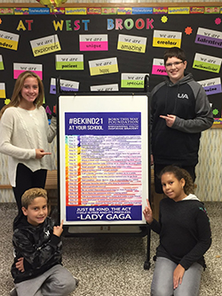 Four students pose with the Lady Gaga challenge poster