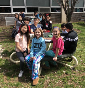 Students gathered sitting around outdoor tables