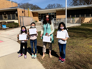Teacher and three female students holding clipboards