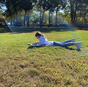 Student reading outside on the grass