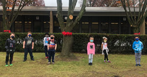 Students standing around trees with red ribbons