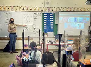 Students learning in the classroom with fellow classmates joining via a Zoom call