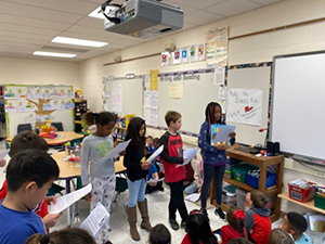 students holding their books in front of the class