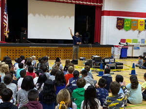 students in the gym listening to a presenter