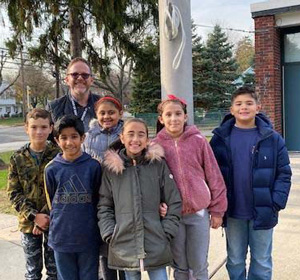 Students and a teacher standing in front of flag pole