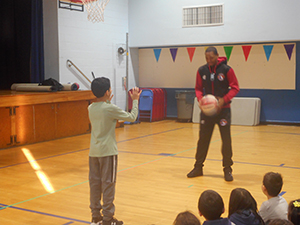 Basketball player passing a basketball to a student