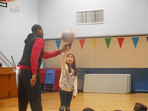 Basketball player showing a student how to spin the basketball on their finger