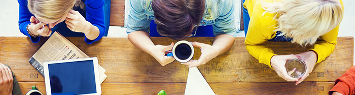Teachers sit at a table as they hold coffee