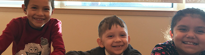 Three happy students sitting at a table smiling for the camera