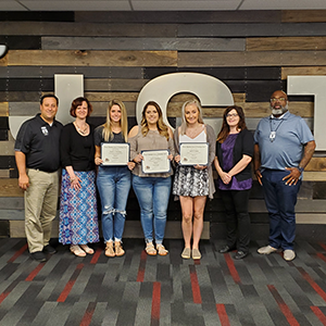 Graduates of the adult cosmetology program pose together with their certificates