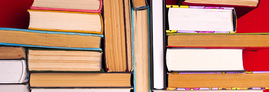 Hardcover books stacked on top of each other behind a bright red background