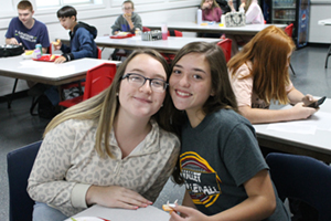 Two girl students smiling in class together