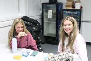 Two grils students eating in classroom together
