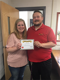 Mrs. Jones and an administrator hold up her award