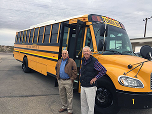 Staff members pose in front of a school bus