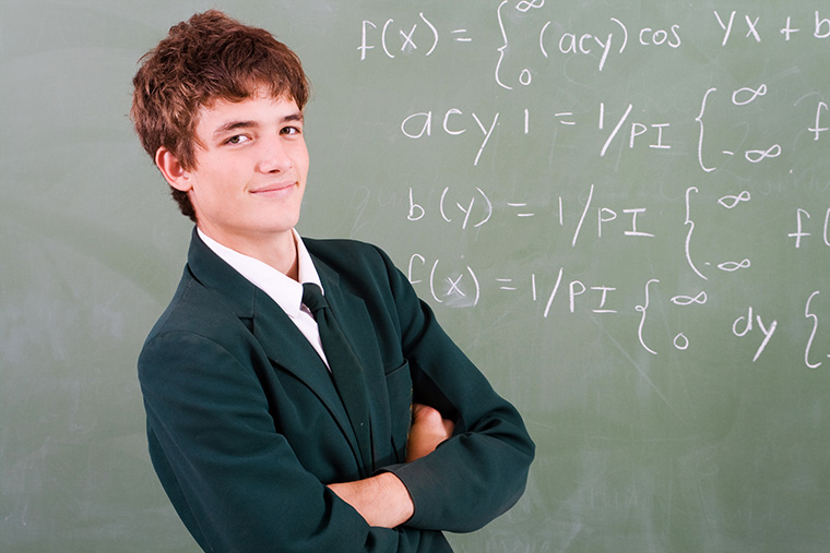 Student poses in front of a blackboard