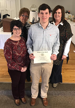 Reid Rushing poses with adults as he holds his certificate