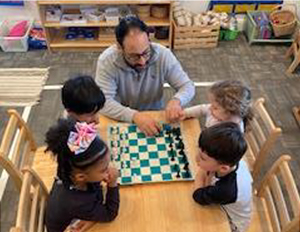 One teacher teaching four students how to play chess.