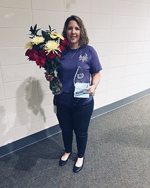 Rachel Sanford holds a vase of flowers and her award as teacher of the year