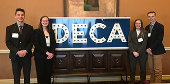 DECA state qualifiers pose together in front of a DECA sign