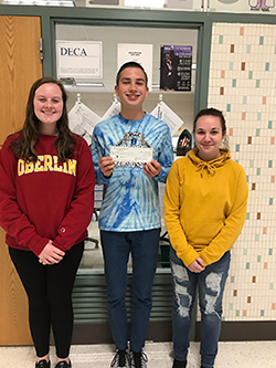 Three students pose with the check for the DECA donation